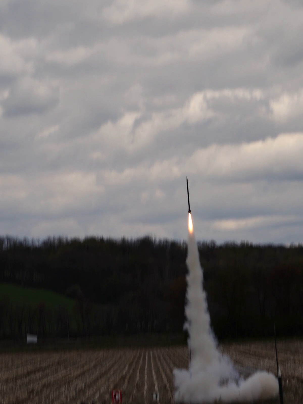 Full-scale vehicle in flight, plume visible above the launch site